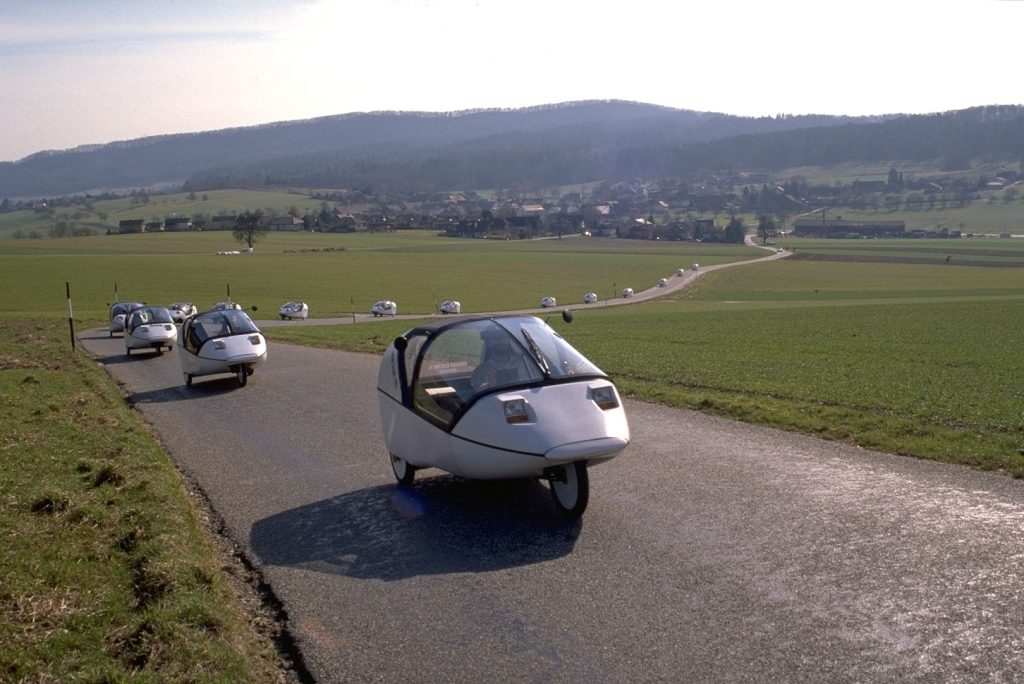 Long convoy of TWIKE 3 vehicles travelling on a rural road
